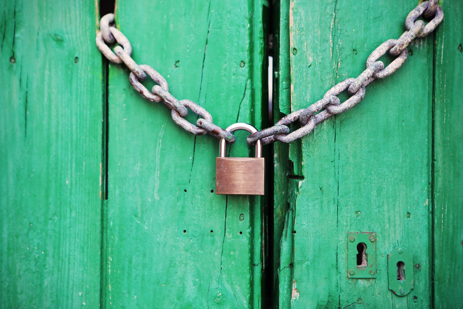 Old Green Wooden Doors Secured with Chain and Padlock